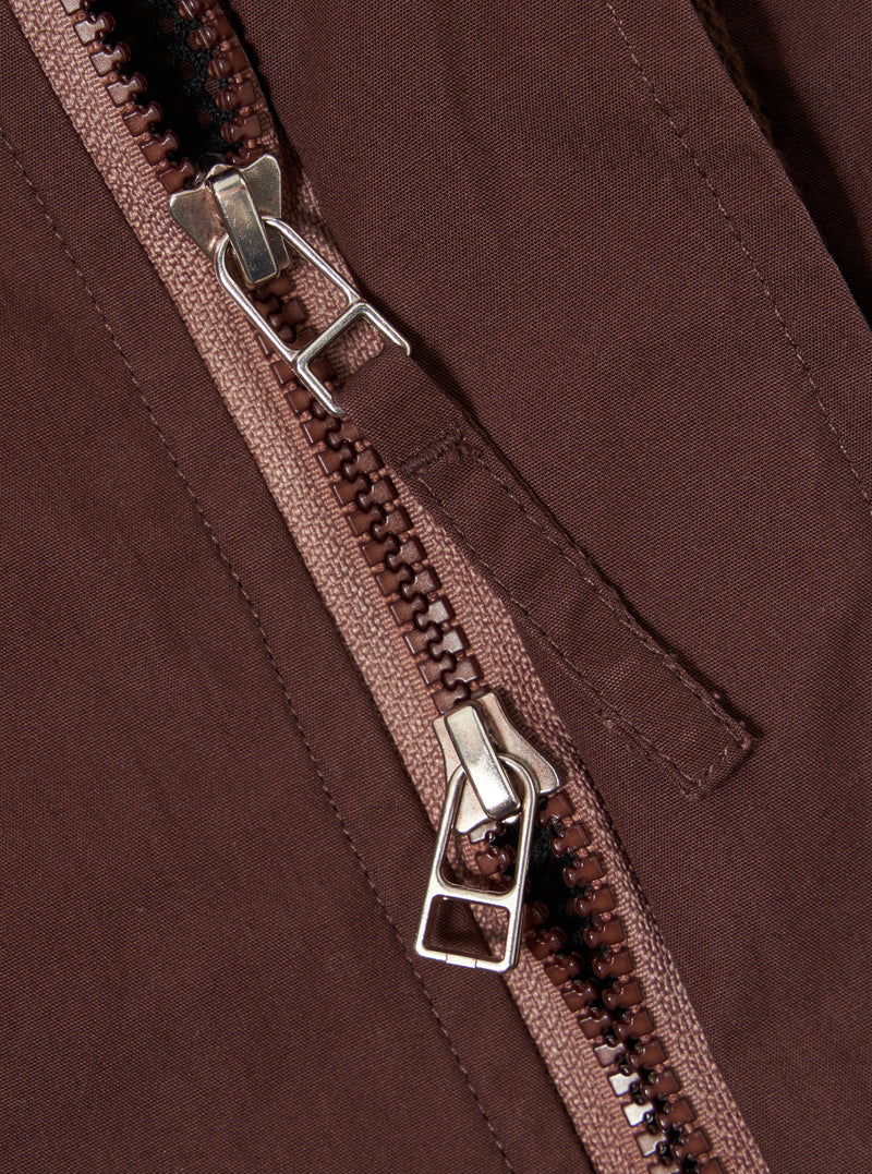 The Brown Peached Poplin NS Bomber Jacket is shown from the back as a flat lay against a plain white background. The image highlights the clean, simple construction of the garment's rear panel, featuring a ribbed collar and set-in sleeves. The peached cotton poplin fabric has a smooth, matte brown finish.