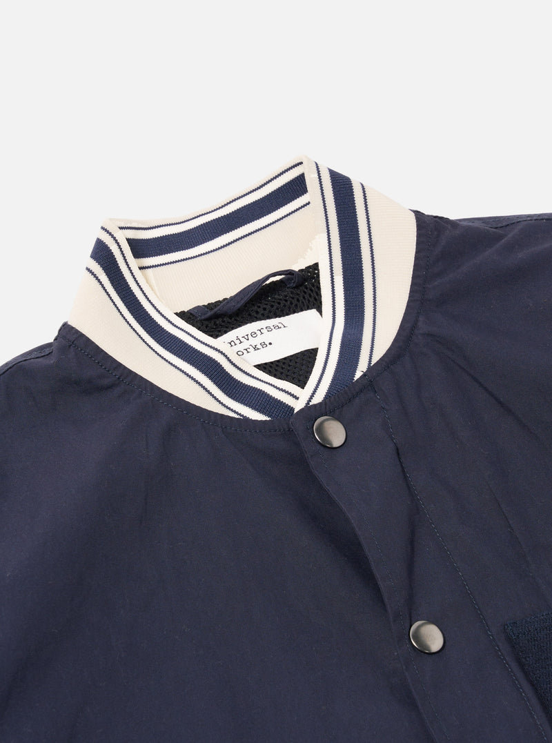The Navy Peached Poplin NS Bomber Jacket is shown from the back as a flat lay against a plain white background. The image highlights the jacket's smooth navy cotton poplin fabric, a central vertical seam, and the contrast stripe ribbing on the collar, cuffs, and hem.