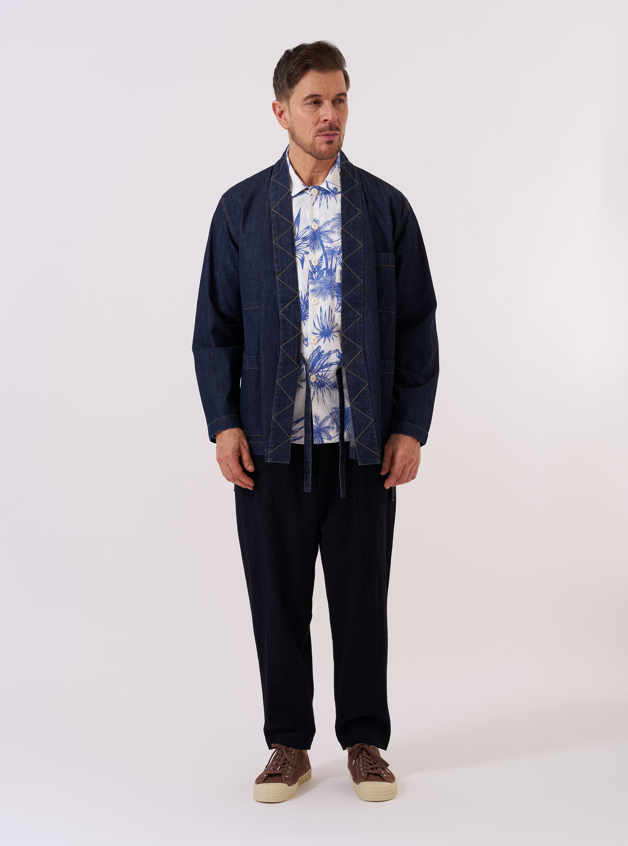 The Indigo Kaihara LT WT Denim Kyoto Work Jacket is shown as a flat lay against a plain white background. The jacket features a collarless, wrap-front design with functional side ties, two lower patch pockets, and a single external chest pocket. The dark indigo denim fabric displays a clean finish with tonal stitching.