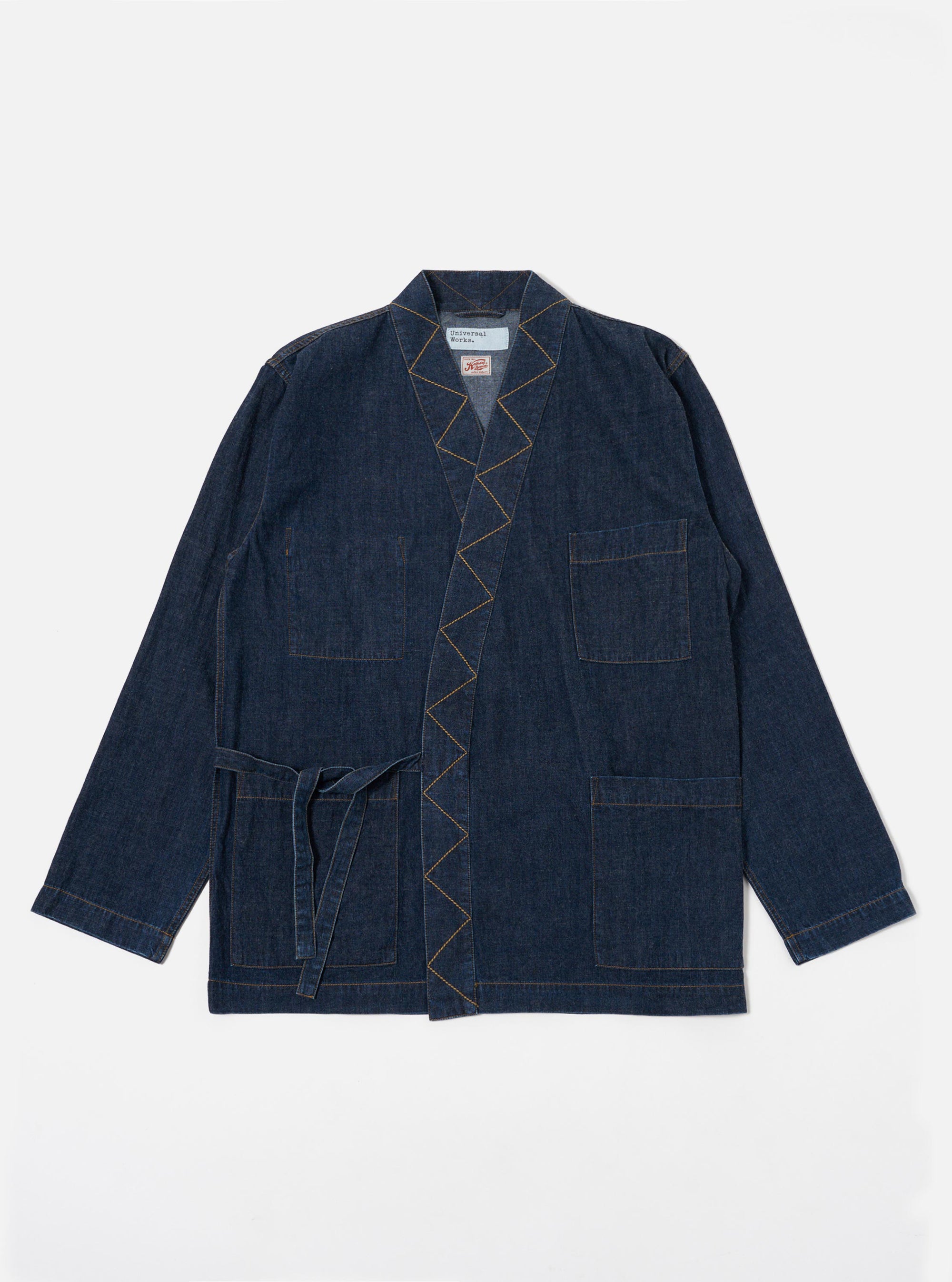 The Indigo Kaihara LT WT Denim Kyoto Work Jacket is shown as a flat lay against a white background. The jacket features a wrap-style front with fabric ties, two large lower patch pockets, and one external chest patch pocket. The garment is made from a lightweight dark indigo denim.