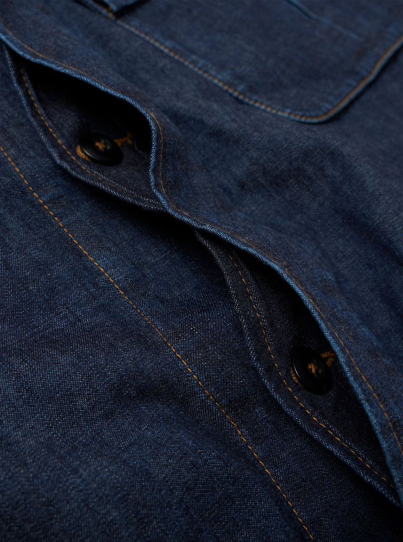 The Indigo Kaihara LT WT Denim Jungle Jacket is shown in a detail view as a flat lay against a plain white background. The image highlights the technical construction of the indigo-dyed cotton denim, focusing on the bottom of the concealed button placket and the two large, pleated, 3D bellowed pockets at the waist.