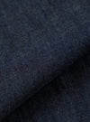 A close-up fabric swatch of the Indigo Kaihara LT WT Denim Hi Water Trouser highlights the deep indigo blue color and the fine diagonal weave of the lightweight denim. The textured material fills the frame, providing a detailed view of the garment's fabric.