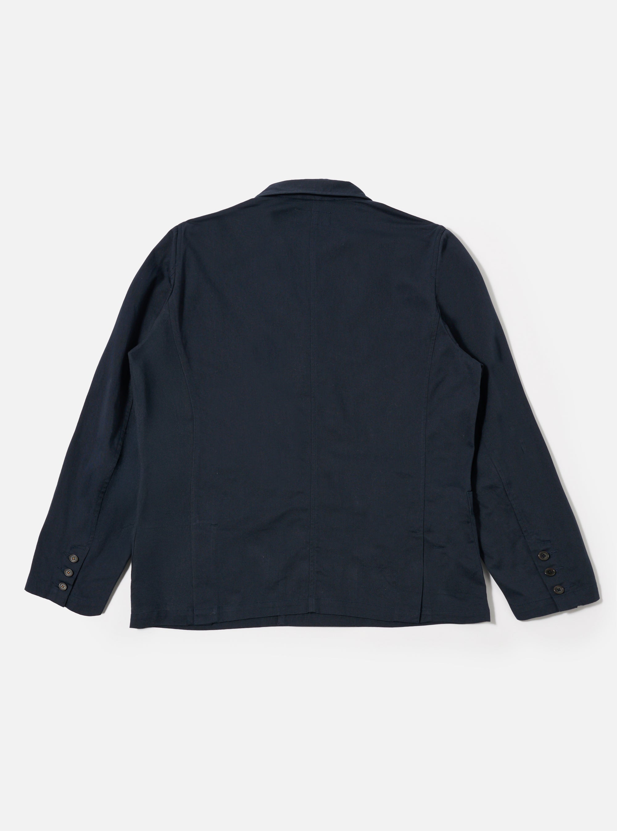The Navy Twill Manor Jacket is shown from a rear angle as a flat lay against a plain white background. The image highlights the double vents at the hem and the structured silhouette of the navy cotton twill fabric.