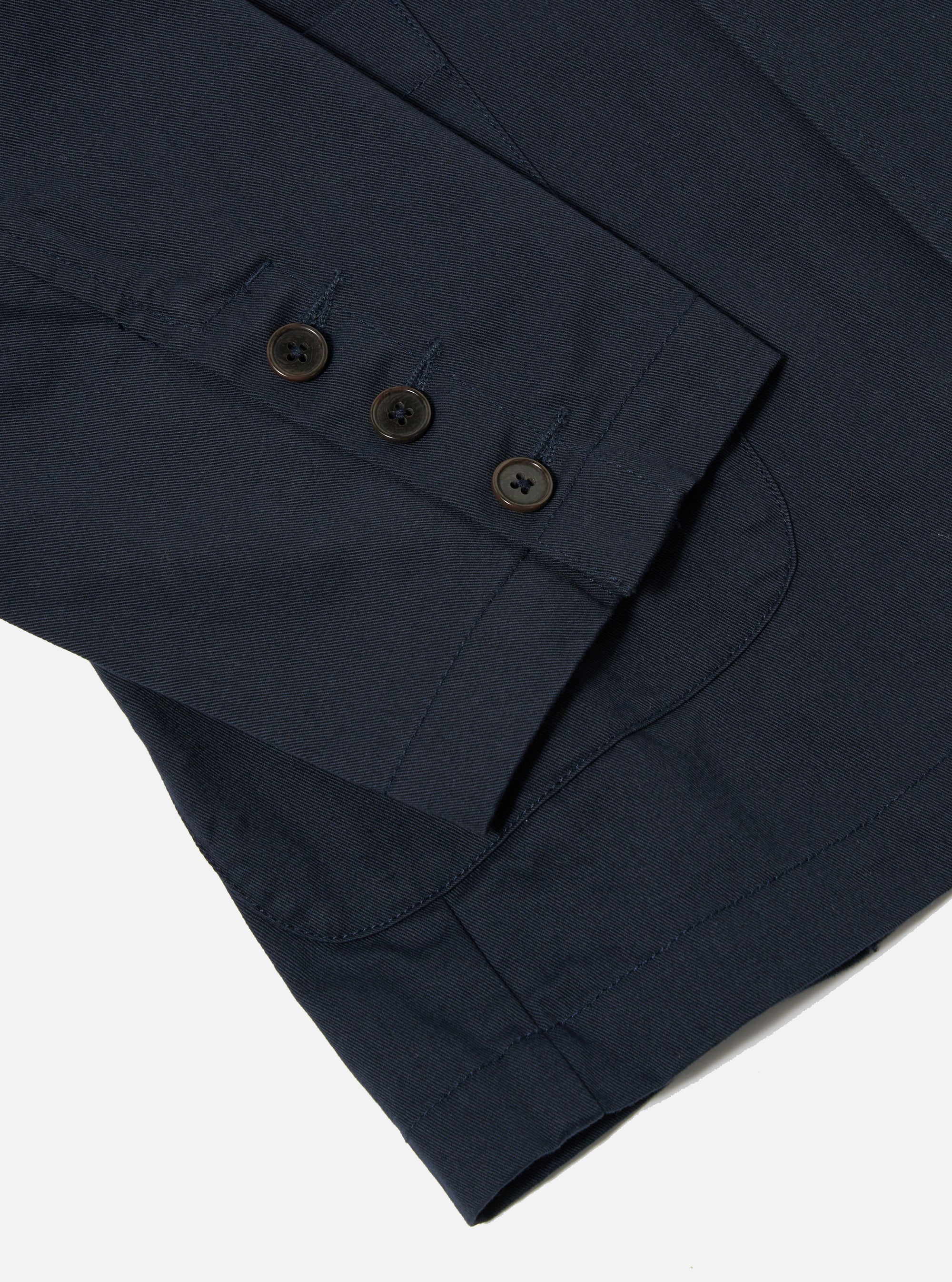The Navy Twill Manor Jacket is shown in a detail view as a flat lay against a plain white background. The image highlights the six-button double-breasted front and the durable, diagonal weave of the navy cotton twill fabric.