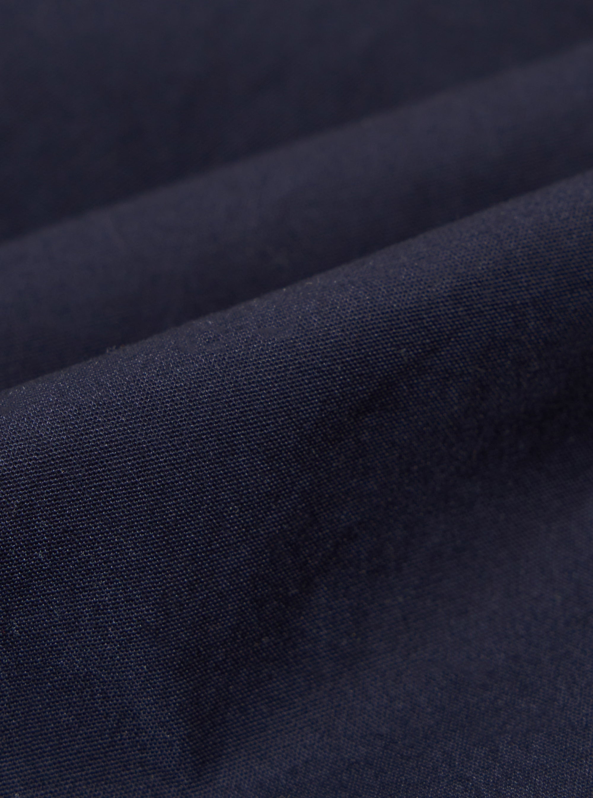 A close-up swatch image of the Navy Peached Poplin Osaka Work Jacket fabric displays a deep navy blue color with a smooth, matte finish. The fine weave of the peached cotton poplin material is clearly visible, filling the frame to highlight its soft texture.