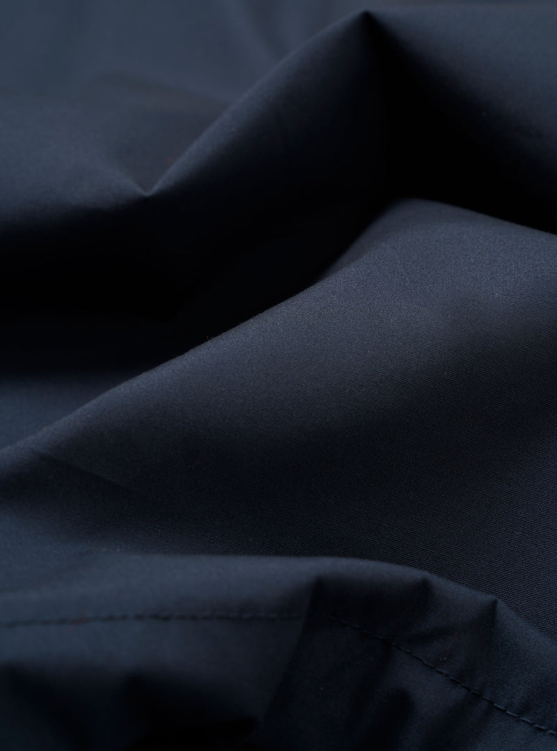 A close-up swatch of the Navy Recycled Polytech Parachute Field Jacket fabric displays a deep navy blue color with a smooth, technical texture. The compact woven material is shown in detail, filling the frame to highlight the utilitarian finish.