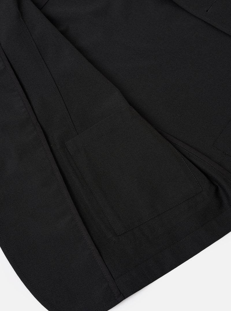 The Black Tropical Suiting Two Button Jacket is shown in a detail view as a flat lay against a plain white background. The image highlights the smooth texture of the black wool-blend fabric, focusing on the two-button front closure and the structured lapels.