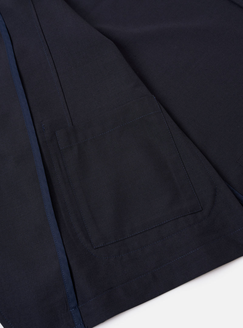 The Navy Tropical Suiting Two Button Jacket is displayed as a flat lay against a plain white background. The jacket features a relaxed, unstructured fit with a two-button front closure and a long, wide notch lapel. Three patch pockets are visible on the front: one at the chest and two larger pockets at the waist. The garment is made from a smooth, lightweight navy blue tropical suiting fabric.