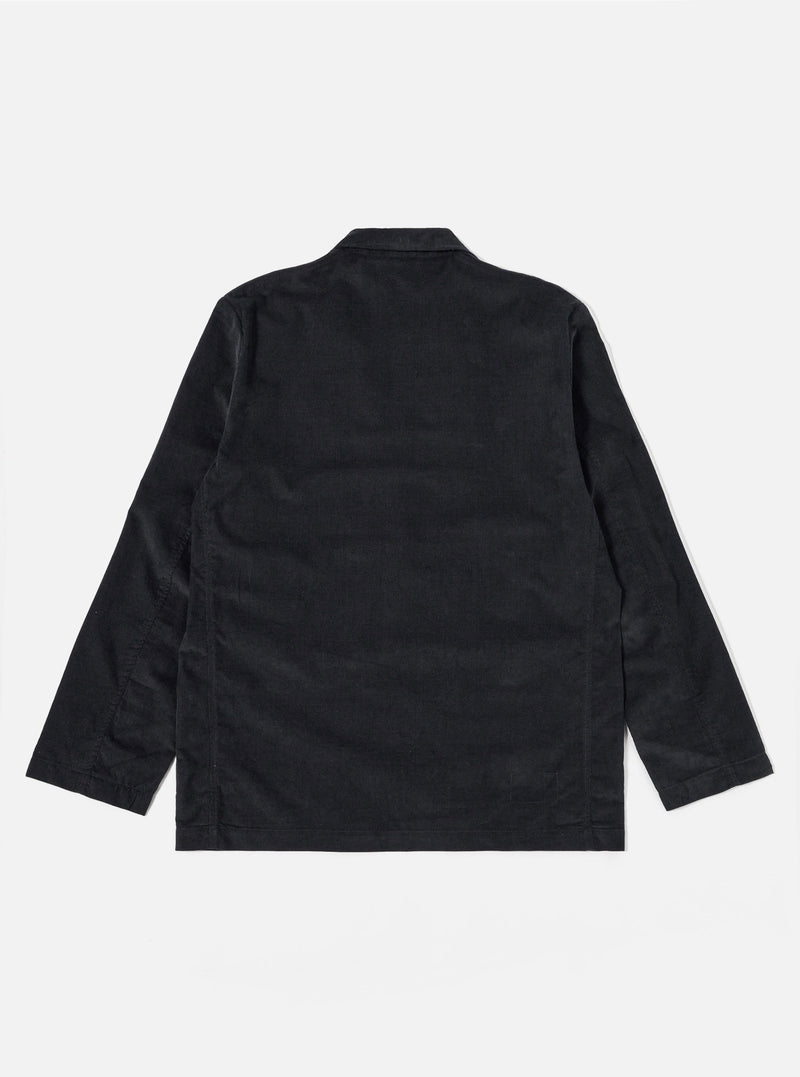 The Black Organic Fine Cord Two Button Jacket is displayed from the back as a flat lay against a plain white background. The image highlights the clean lines of the garment, featuring a central vent at the hem and a structured two-piece sleeve construction. The fine-ribbed texture of the black organic cotton corduroy is visible across the entire surface.