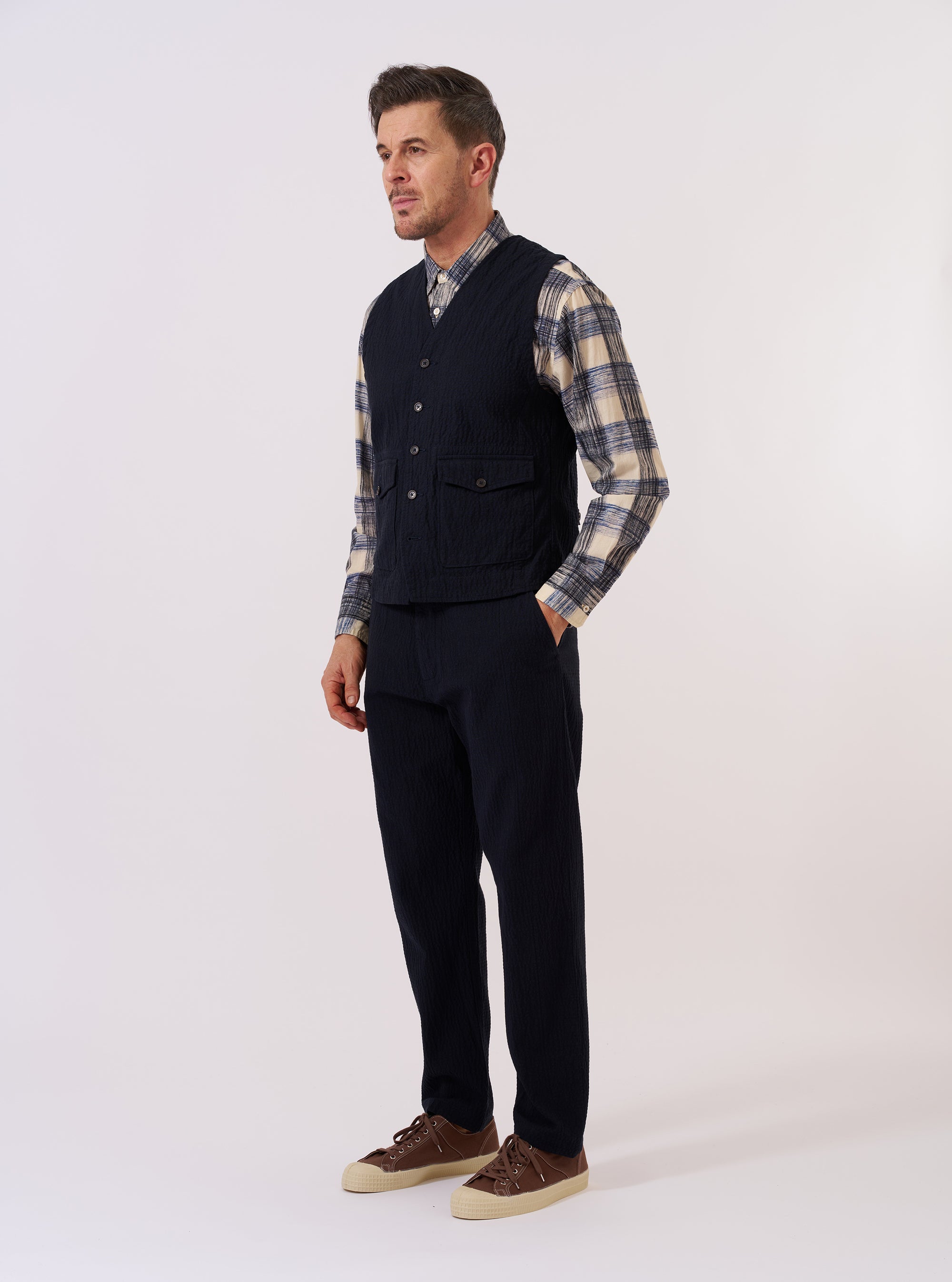 The Dark Navy Ospina Cotton Field Waistcoat is shown as a flat lay against a plain white background. The waistcoat features a structured collar, a central button-down closure, and four large patch pockets on the front. The dark navy fabric has a subtle seersucker texture.