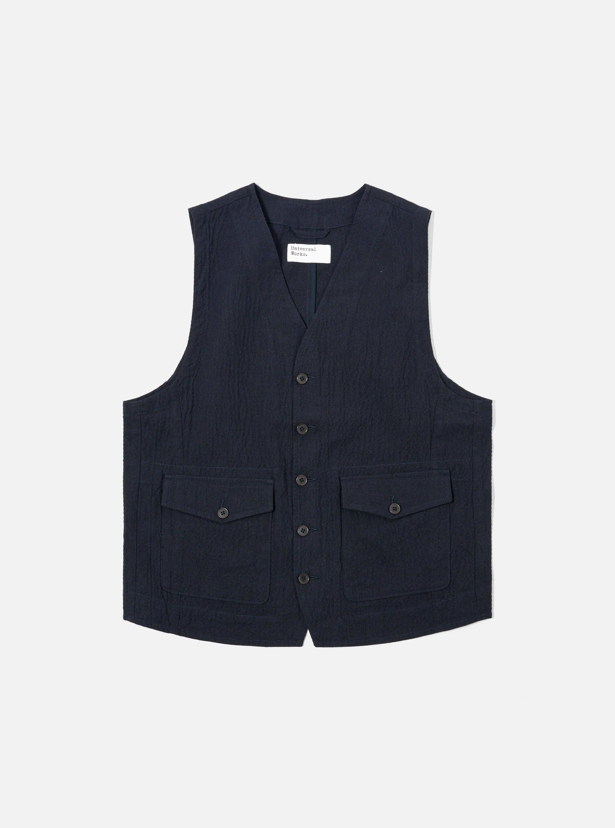 The Dark Navy Ospina Cotton Field Waistcoat is shown as a flat lay against a white background. The waistcoat features four large front patch pockets, a five-button closure, and a structured collar. The fabric has a visible seersucker texture.