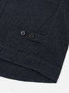 The Dark Navy Ospina Cotton Field Waistcoat is shown in a detail view as a flat lay against a plain white background. The image highlights the textured seersucker finish of the dark navy fabric and the construction of the functional patch pockets.