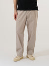 A model wears the Brown Kennedy Stripe Duke Pant, shown from the waist down against a plain white background. The trousers feature a loose, wide-leg fit with a brown and cream vertical stripe pattern throughout. They are styled with a tucked-in shirt and dark shoes, highlighting the pleated front and relaxed silhouette of the garment.