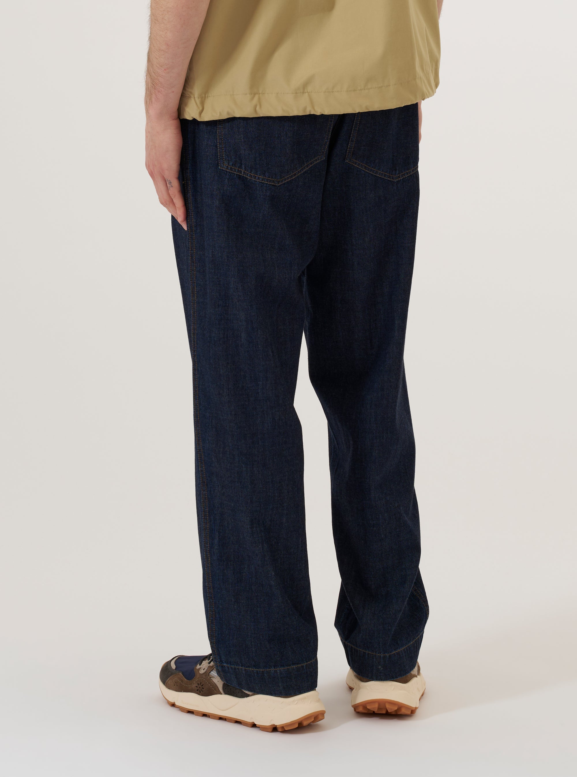 A model wears the Indigo Kaihara LT WT Denim Duke Pant, shown from the rear three-quarter angle against a plain white background. The image highlights the wide-leg fit with a slight taper, the fixed waistband, and two large rear patch pockets. The indigo-dyed denim fabric features visible texture and tonal stitching. No mannequin is present in the image.