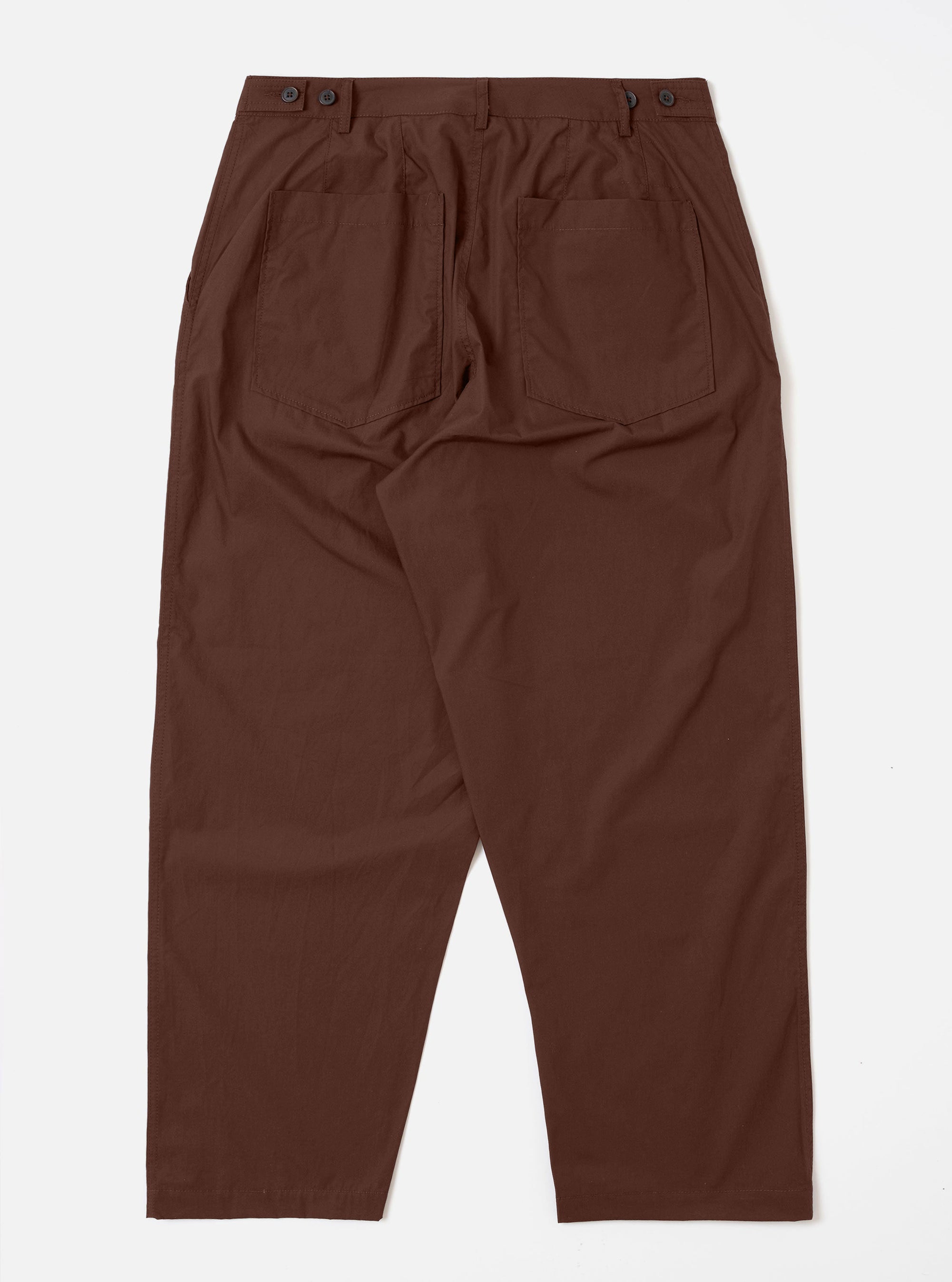 The Brown Peached Poplin Dutch Pant is shown from the rear in a flat lay against a white background. The image highlights the two square rear patch pockets and the loose, wide-leg construction of the brown cotton trousers.