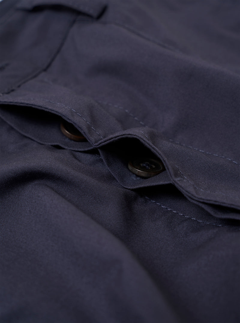 The Navy Peached Poplin Dutch Pant is shown as a flat lay against a white background. The trousers feature a wide-leg fit, an elasticated waistband with a drawstring, two large front patch pockets, and a single rear buttoned pocket. The peached cotton fabric has a soft, matte finish.