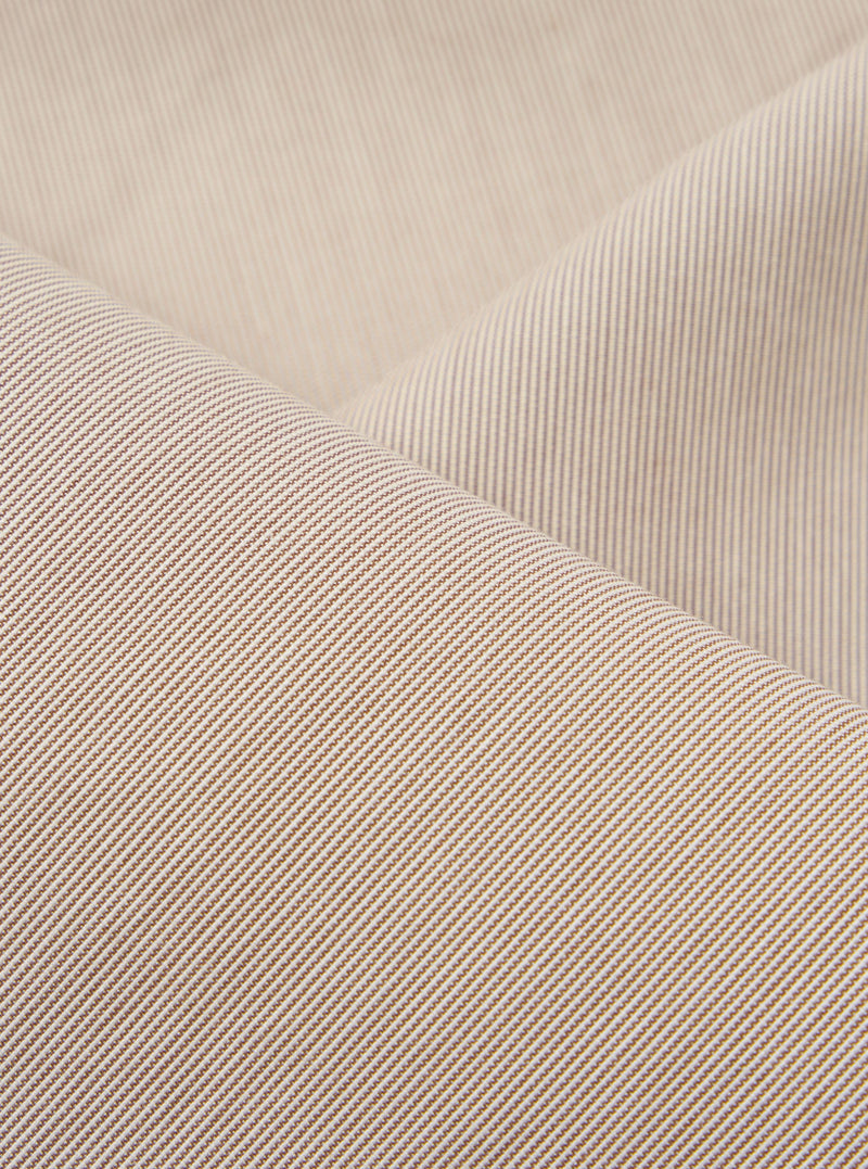 A close-up fabric swatch of the Brown Kennedy Stripe Hi Water Trouser highlights the brown vertical stripe pattern and the texture of the cotton fabric. The material fills the frame, providing a detailed view of the garment's color and construction.