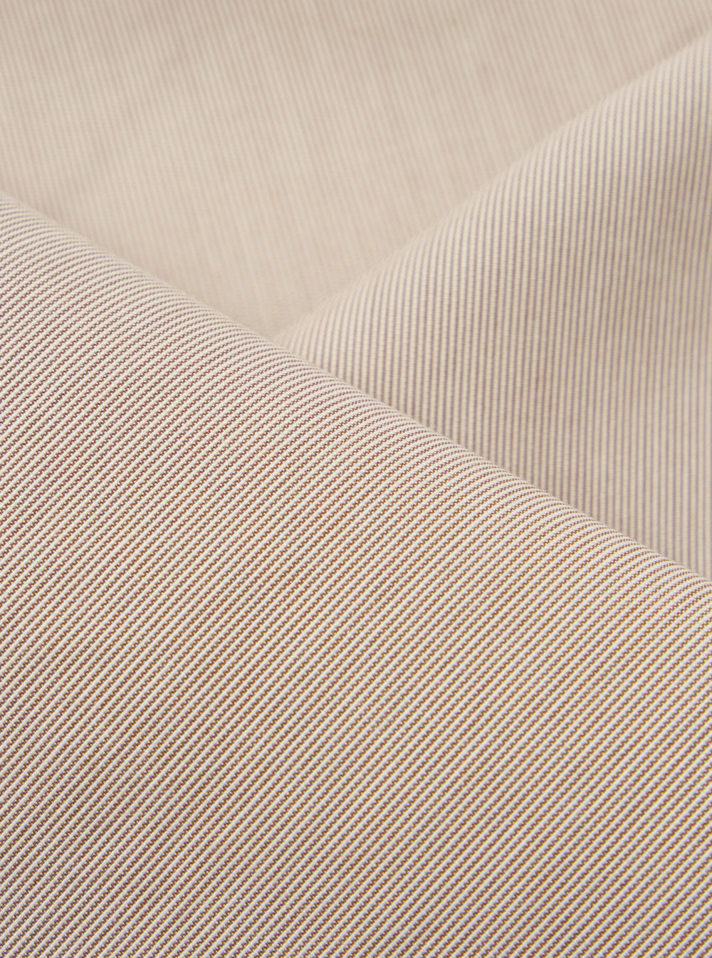 A close-up fabric swatch of the Brown Kennedy Stripe Hi Water Trouser highlights the brown vertical stripe pattern and the texture of the cotton fabric. The material fills the frame, providing a detailed view of the garment's color and construction.