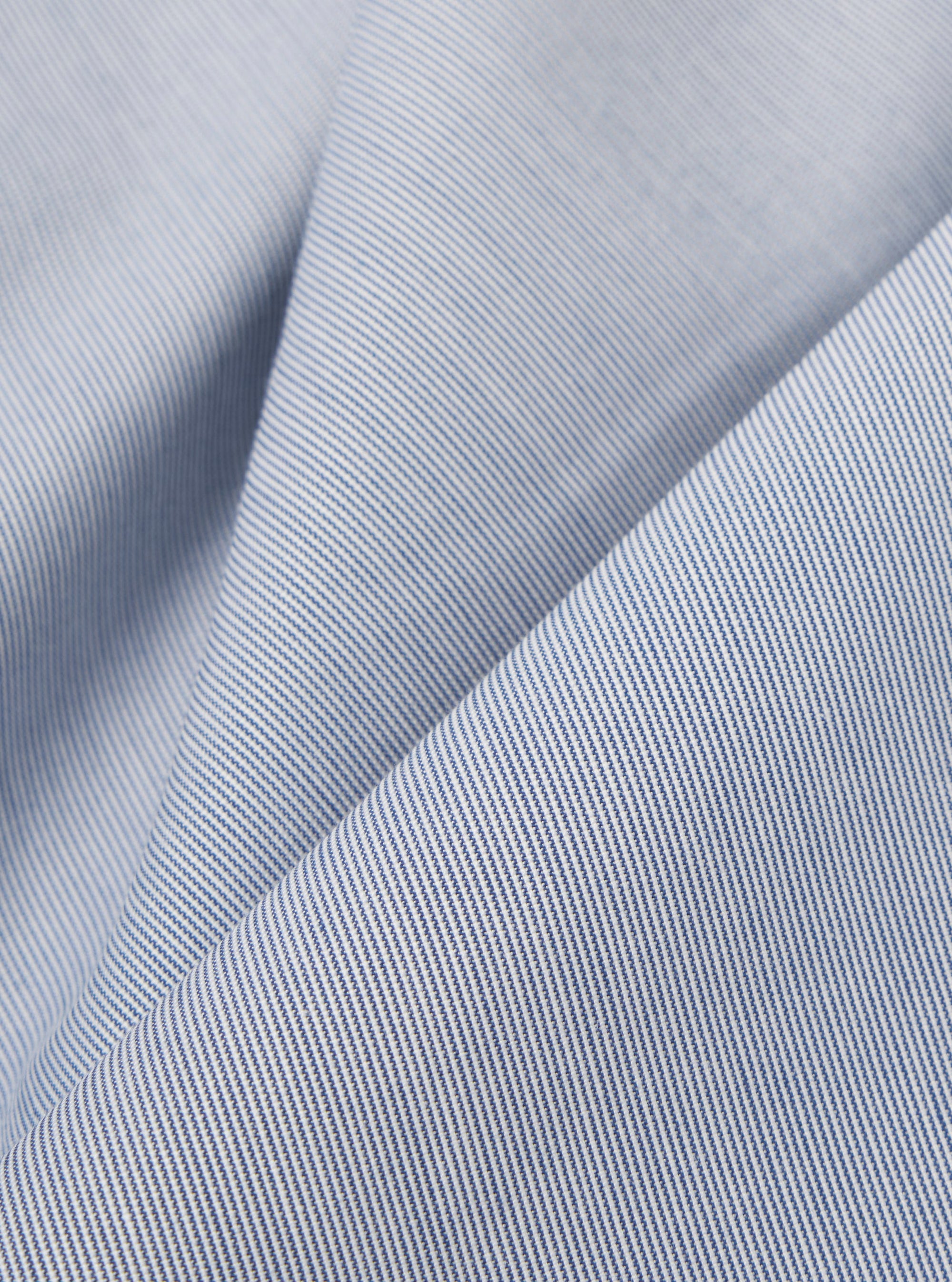 A close-up fabric swatch of the Navy Kennedy Stripe Hi Water Trouser displays a dark navy blue base with thin, vertical white stripes. The detailed view highlights the fine weave of the cotton fabric and the consistent spacing of the pinstripe pattern.