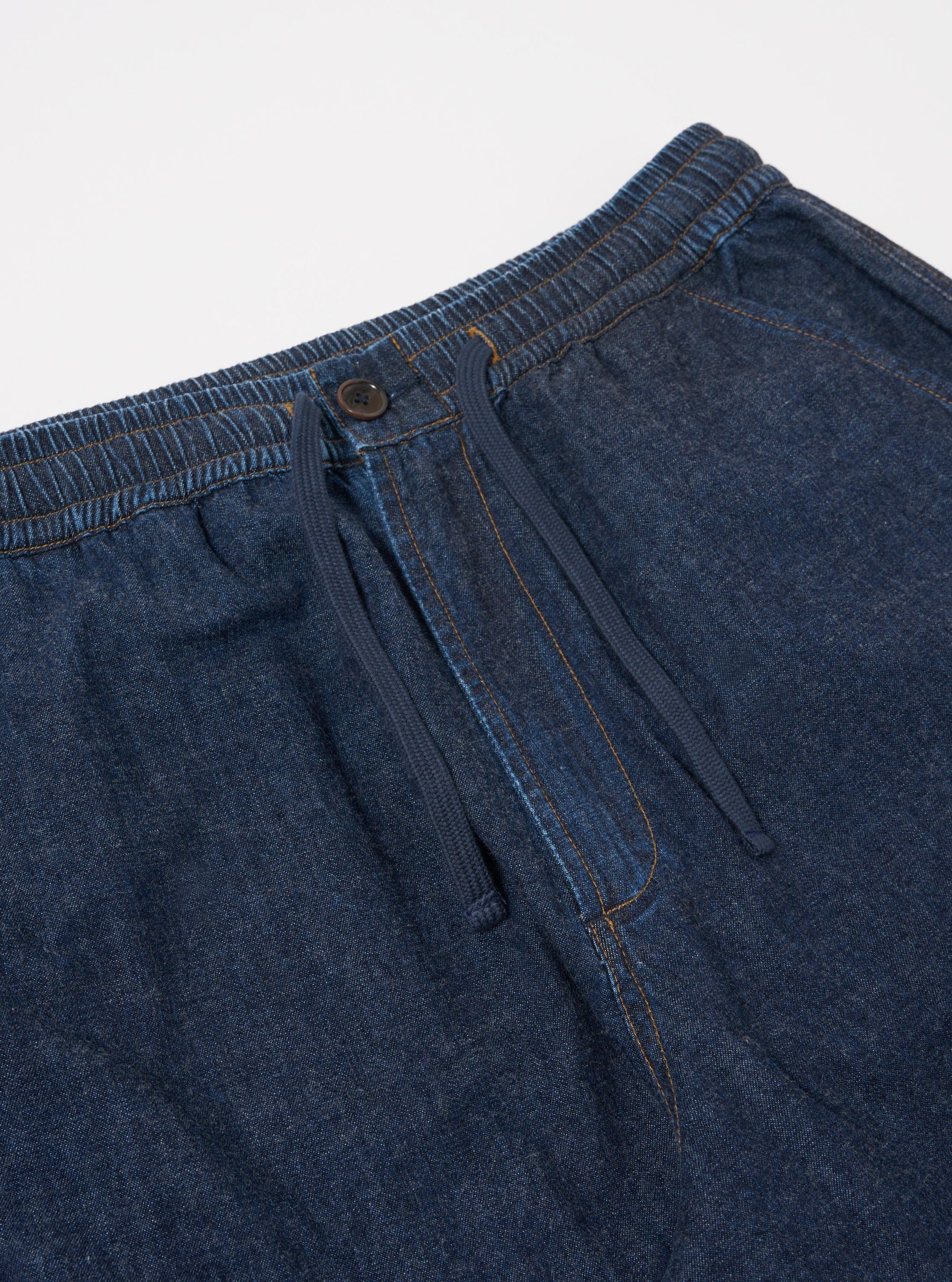 The Indigo Kaihara LT WT Denim Hi Water Trouser is shown from a rear angle as a flat lay against a plain white background. The image highlights the elasticated waistband and two large rear patch pockets. The lightweight indigo denim fabric features a subtle texture and visible stitching details.