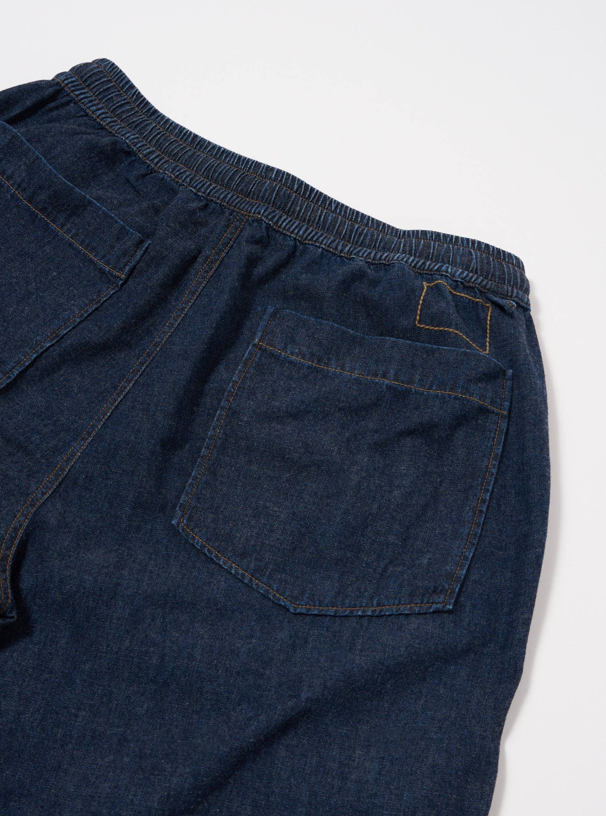 The Indigo Kaihara LT WT Denim Hi Water Trouser is shown from the back as a flat lay against a plain white background. The image highlights the two rear patch pockets, the elasticated waistband with a drawstring, and the clean finish of the hems. The dark indigo denim fabric has a smooth, lightweight appearance.