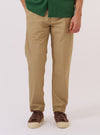 A model wears the Sand Recycled Polytech Military Chino, shown from the waist down against a plain white background. The trousers feature a slim-straight fit, side slant pockets, and a button-through rear flap pocket. The technical recycled polytech fabric is a solid sand color with a smooth, matte finish. The model is wearing a white T-shirt tucked into the waistband and white socks with black shoes.