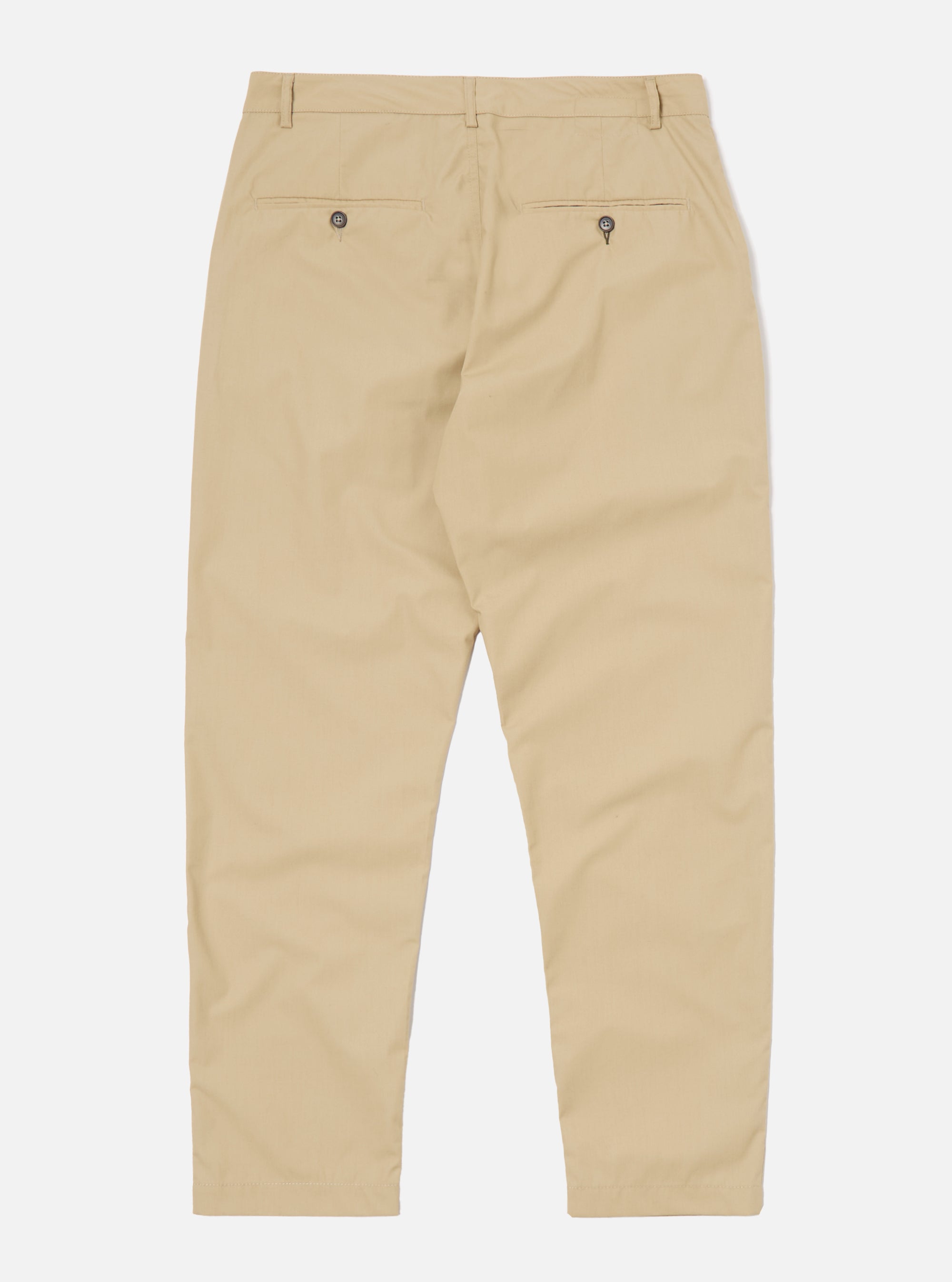 The Sand Recycled Polytech Military Chino is shown from a rear three-quarter angle as a flat lay against a plain white background. The image highlights the two rear jetted pockets with button closures and the tapered leg construction. The light sand-colored fabric has a smooth, technical finish.
