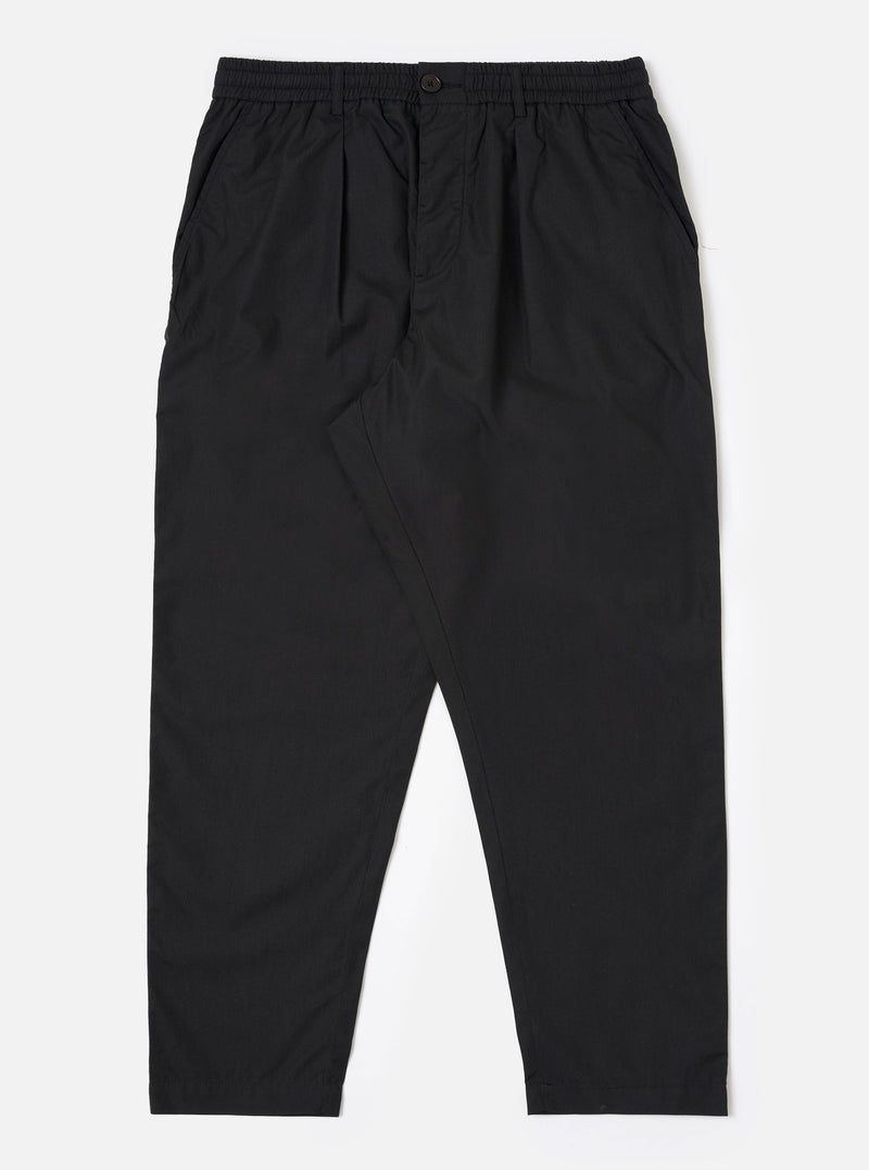 The Black Recycled Polytech Pleated Track Pant is displayed as a flat lay against a plain white background. The trousers feature an elasticated waistband with a tonal drawstring, a single front pleat on each leg, and a relaxed, tapered silhouette. The black fabric has a smooth, technical finish.