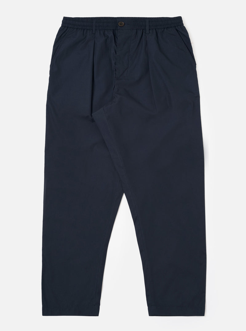 The Navy Recycled Polytech Pleated Track Pant is displayed as a flat lay against a plain white background. The trousers feature a loose, tapered fit with a single pleat at the front, an elasticated waistband with a tonal drawstring, and two side pockets. The dark navy recycled polytech fabric has a smooth, clean finish.