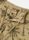 The Sand Jungle Toile Twill Pleated Track Short is shown from the back as a flat lay against a plain white background. The shorts feature a relaxed fit, an elasticated waistband, and two rear patch pockets, with the right pocket featuring a button-down flap. The sand-colored cotton twill fabric is covered in a dark, detailed jungle toile print featuring botanical and animal illustrations.