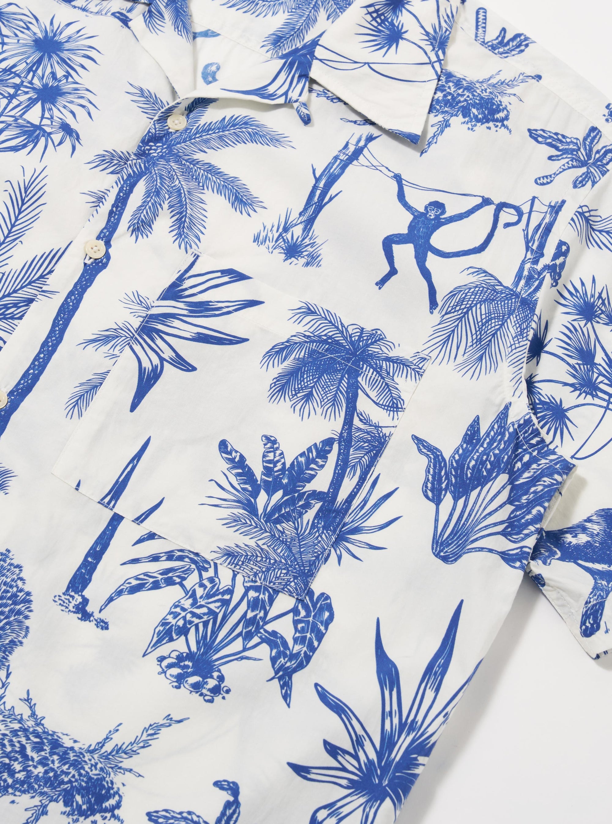 The White Jungle Toile Poplin Camp Shirt is shown from the back as a flat lay against a plain white background. The image highlights the straight hem, the back of the camp collar, and the intricate jungle-themed print featuring dark botanical and animal illustrations on a white base.