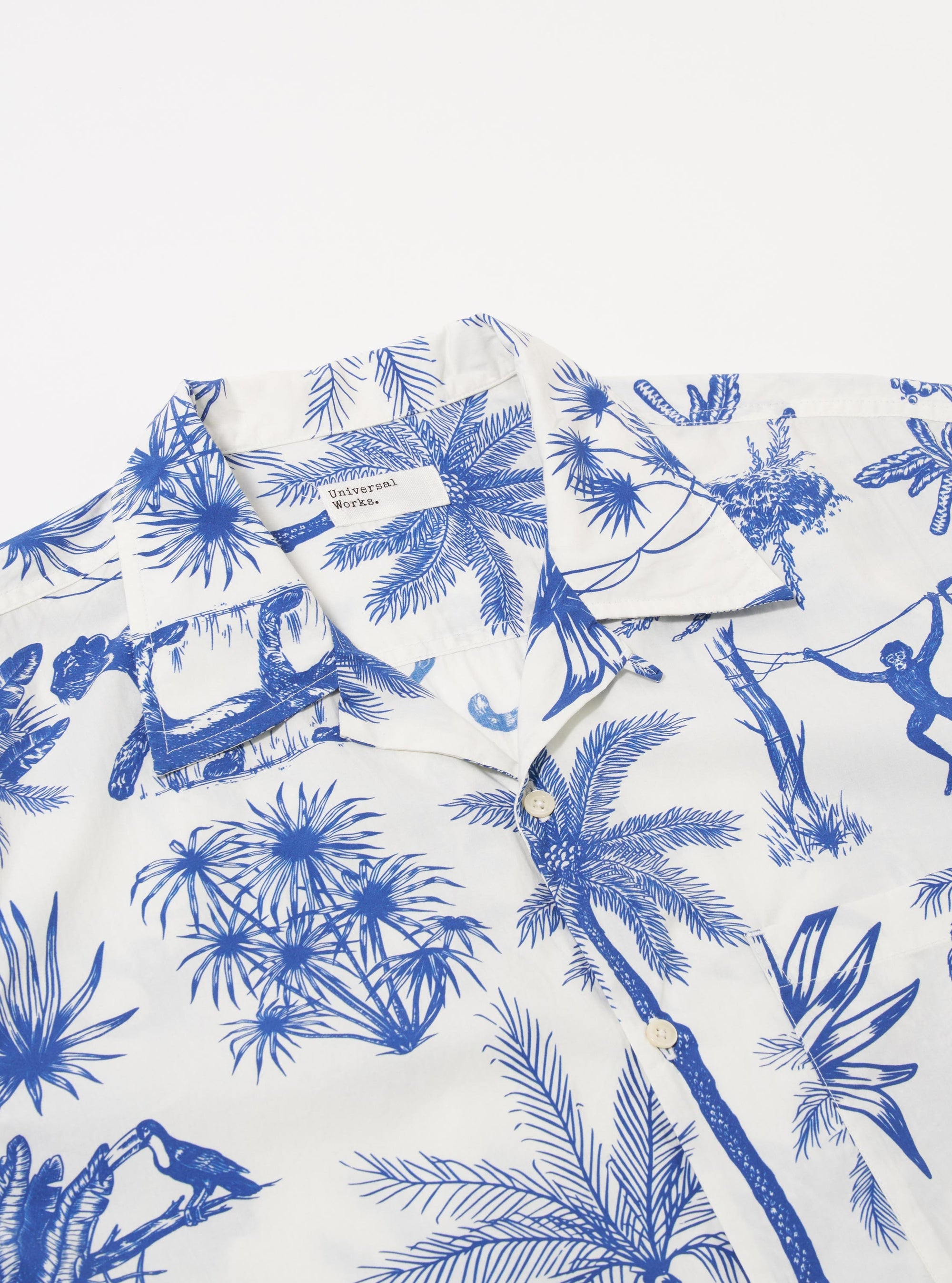 The White Jungle Toile Poplin Camp Shirt is shown from the back as a flat lay against a plain white background. The shirt features a straight hem, a simple back yoke, and a continuous jungle toile print with dark botanical and animal illustrations on an ecru base. The fabric appears lightweight with a smooth poplin texture.