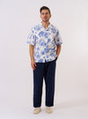 The White Jungle Toile Poplin Camp Shirt is shown as a flat lay against a white background. The shirt features a camp collar, a single chest patch pocket, and a central button-down front. The fabric is a white cotton poplin decorated with a detailed jungle toile print featuring animals and tropical foliage in a dark ink.