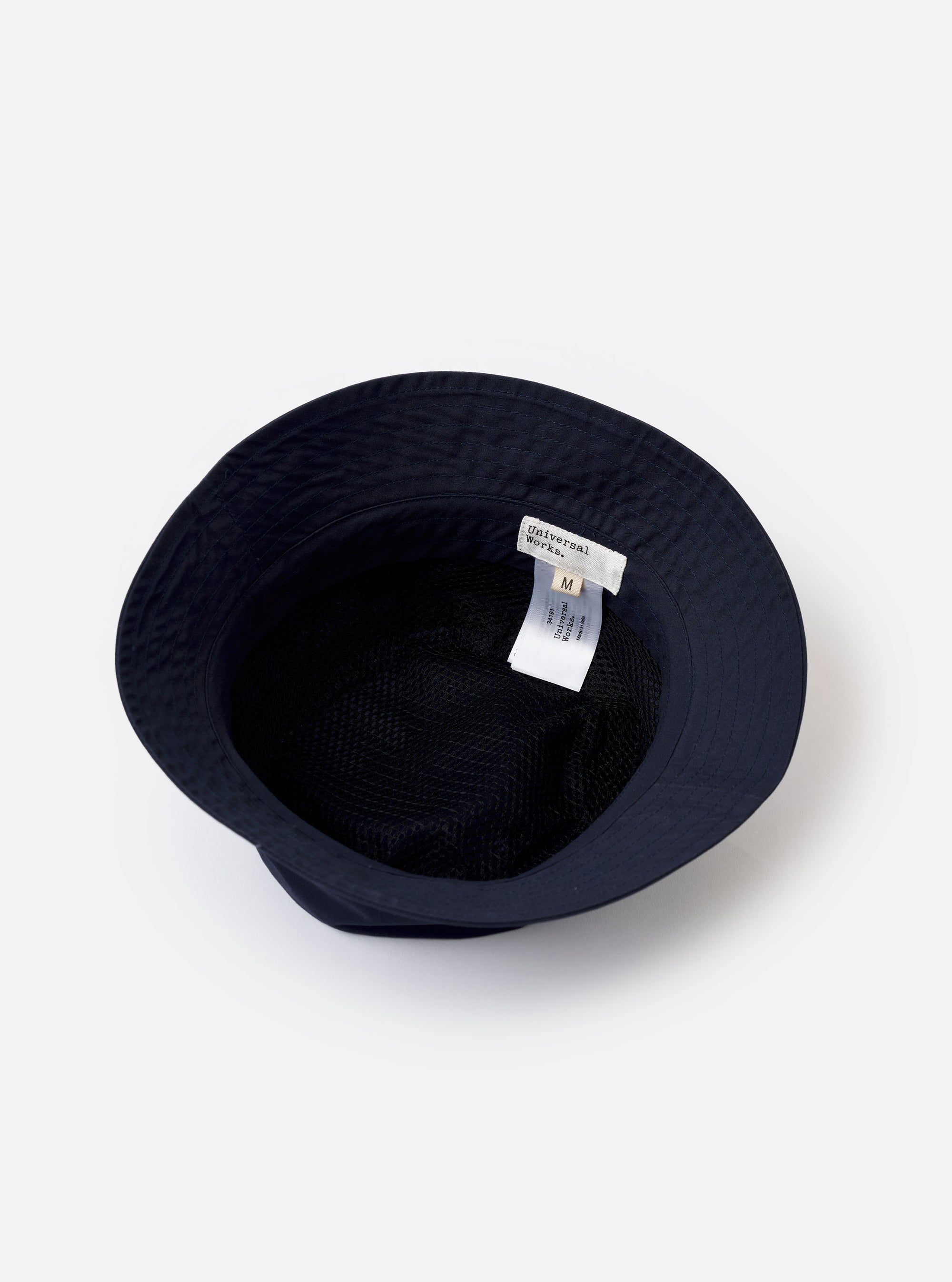 The Navy Recycled Polytech Beach Hat is shown from a side angle as a flat lay against a plain white background. The bucket-style hat features a structured crown with tonal stitching and a wide, downward-sloping brim. The dark navy fabric has a smooth, technical finish.