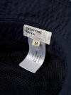 The Navy Recycled Polytech Beach Hat is shown in a detail view as a flat lay against a plain white background. The image highlights the interior of the bucket hat, showing the mesh lining, the brand label, and the internal sweatband. The dark navy fabric and the dual metal ventilation eyelets on the side are also visible.