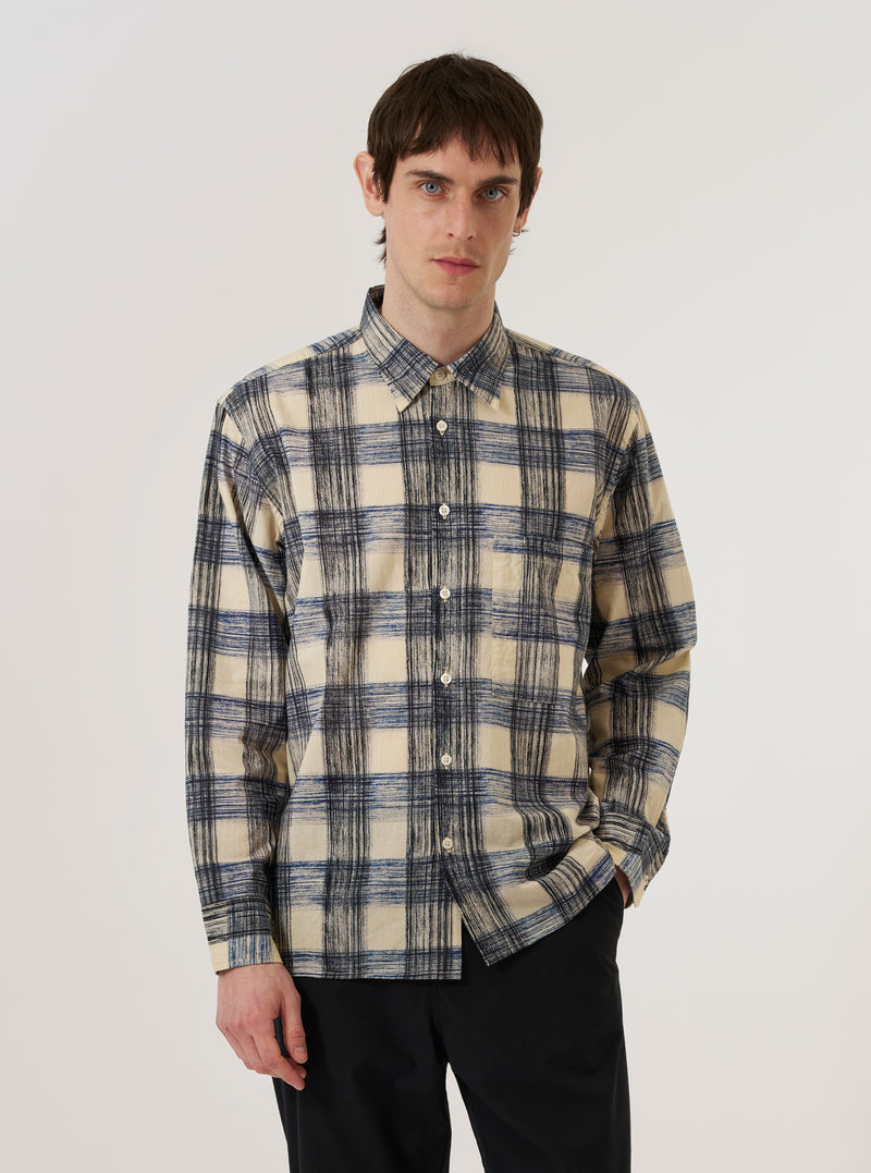 A model wears the Navy Window Panes Square Pocket Shirt against a plain white background. The shirt features a dark navy base with a white windowpane check pattern, a classic button-down front, and a prominent square patch pocket on the left chest. The model is shown from the waist up, with the shirt tucked into light-colored trousers, highlighting the garment's regular fit and crisp collar.