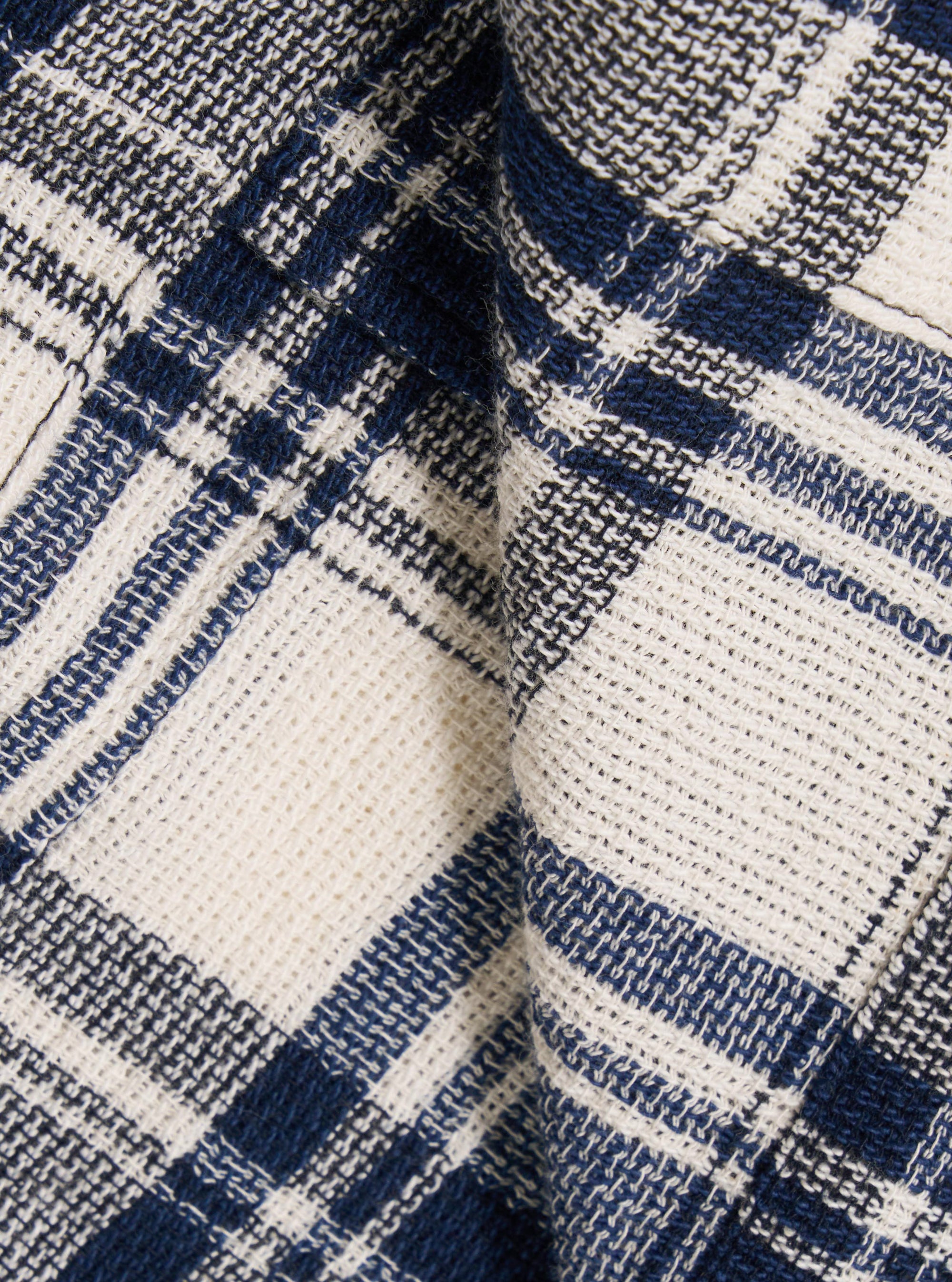 A close-up swatch image of the Navy Texture Plaid Cancun Jacket fabric highlights the intricate navy blue and white plaid pattern. The image focuses on the textured weave of the cotton material, showing the intersecting lines that create the plaid design.