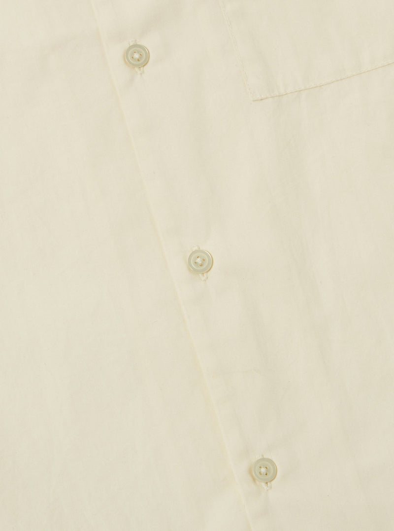 Close-up of the A. SOCIETY x Universal Works Ecru Broadcloth Camp Shirt. Shows the ecru color, broadcloth material, and button details. Shot on a flat surface.