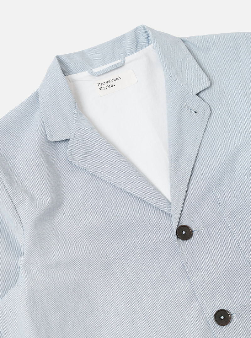 The Navy Kennedy Stripe Three Button Jacket is shown from the back as a flat lay against a plain white background. The jacket features a vertical pinstripe pattern, a central rear vent, and structured shoulders. The navy cotton fabric has a crisp, tailored appearance.