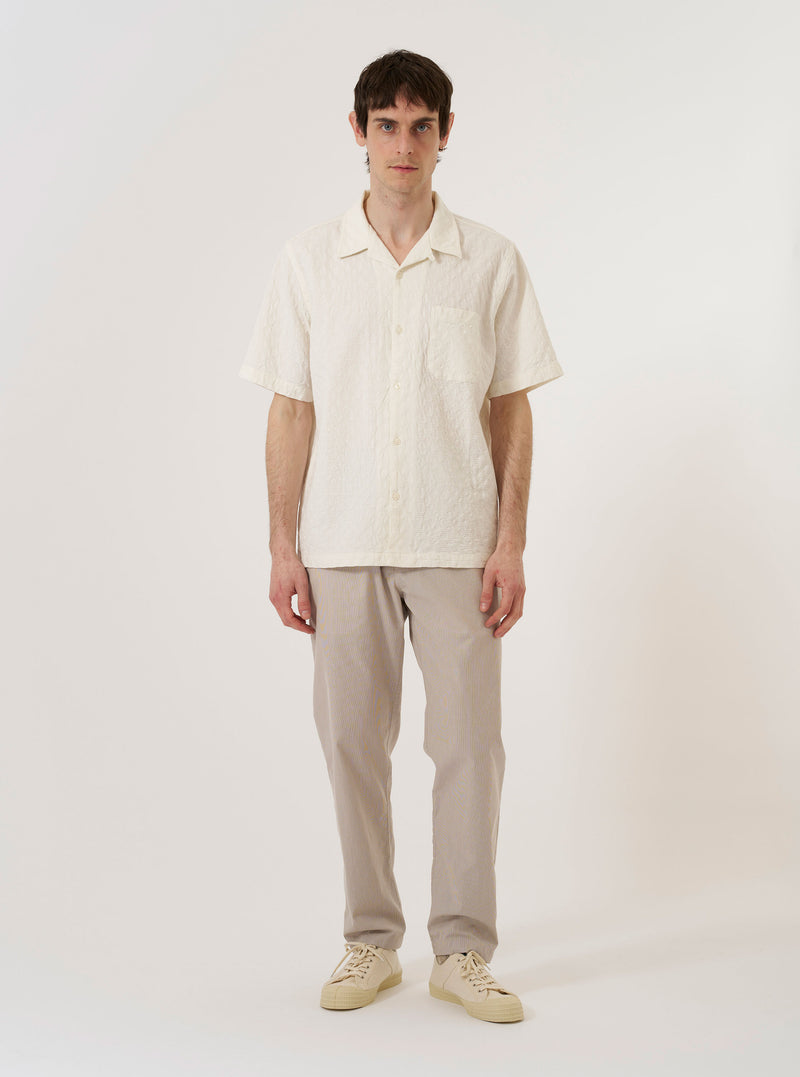 The Brown Kennedy Stripe Military Chino is shown as a flat lay against a plain white background. The trousers feature a straight-leg silhouette with a vertical pinstripe pattern throughout. Prominent details include a button waist closure, belt loops, and two front slant pockets.