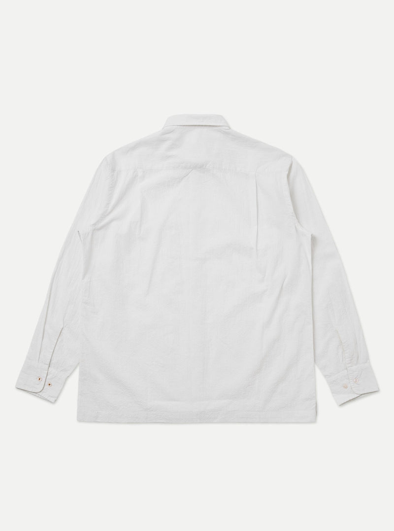 A close-up fabric swatch of the White Seersucker Double Lucky Shirt displays a crisp white color with the characteristic puckered, rippled texture of seersucker. The fine, alternating tighter and looser cotton warp threads create a series of small, raised ridges across the surface of the material. There is no model or mannequin present in the image.