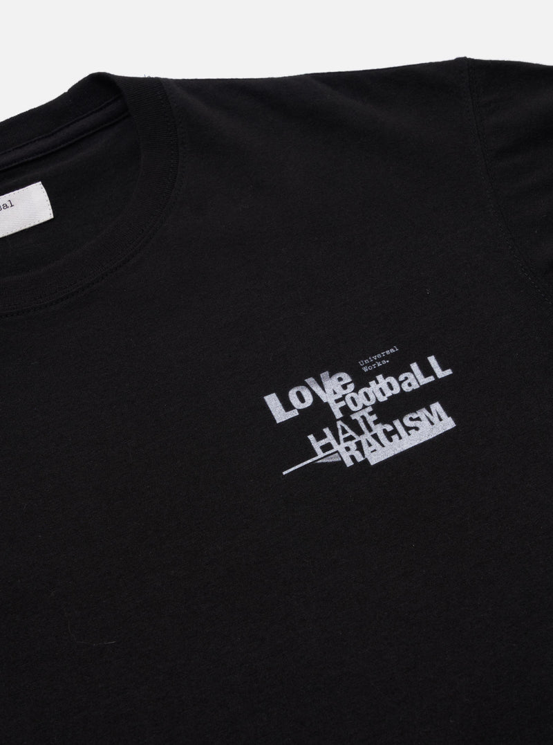 The Black Love Football Jersey Print Tee is shown from the back as a flat lay against a plain white background. The image highlights the clean construction of the rear panel, the short sleeves, and the ribbed crew neck. The garment is made from a solid black cotton jersey fabric.