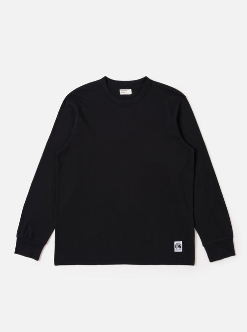 The Black Recycled/Bio Jersey Henry L/S Tee is presented as a flat lay against a plain white background. This long-sleeve t-shirt features a crew neckline, ribbed cuffs, and a straight hem. The garment is made from a solid black recycled and organic cotton jersey fabric.