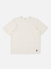 The Antique White Recycled/Bio Jersey Core Pocket Tee is shown as a flat lay against a plain white background. The T-shirt features a classic crew neckline, short sleeves, and a single patch pocket on the left chest. The fabric is a solid antique white jersey with a smooth texture.