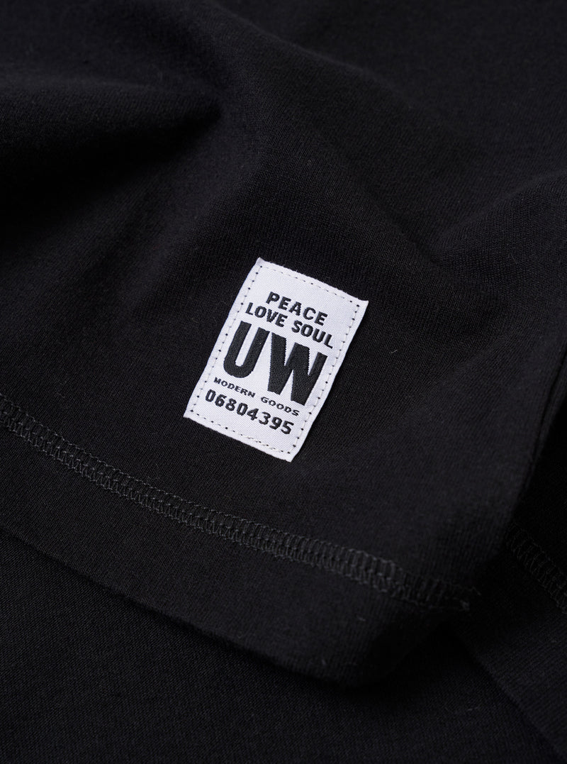 The Black Recycled/Bio Jersey Core Pocket Tee is shown from the back as a flat lay against a plain white background. The image highlights the simple, clean construction of the garment's rear, featuring short sleeves and a straight hem. The fabric is a smooth black jersey made from a blend of recycled and organic cotton.
