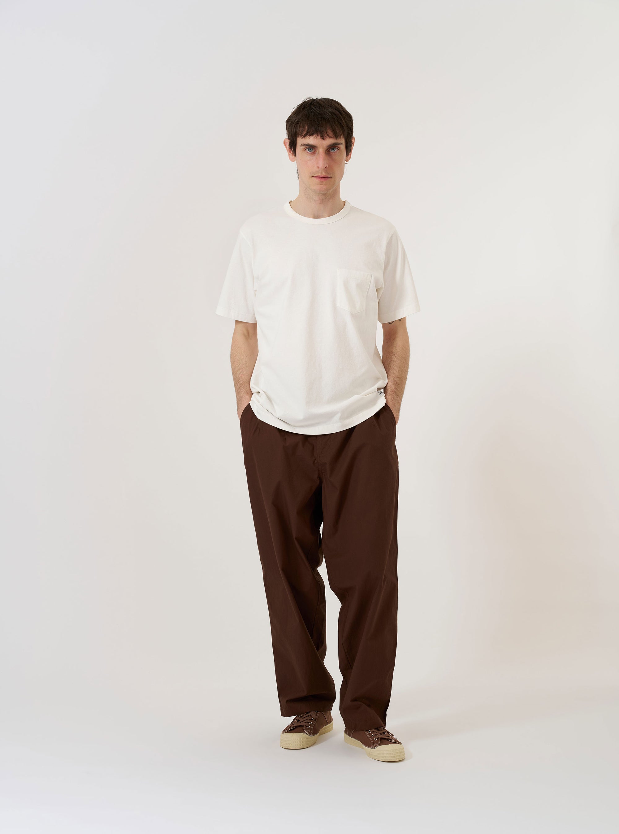 The Antique White Recycled/Bio Jersey Core Pocket Tee is shown as a flat lay against a plain white background. The T-shirt features a classic crew neckline, short sleeves, and a single patch pocket on the left chest. The garment is made from a smooth, antique white jersey fabric.