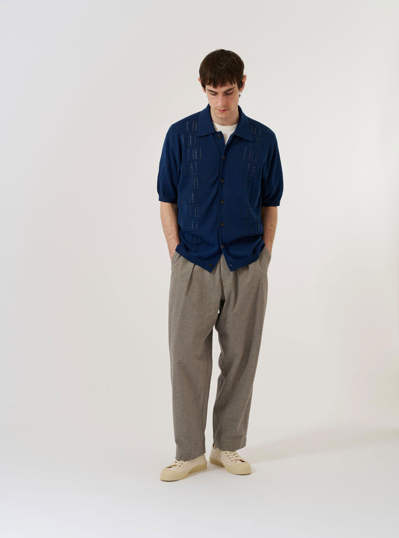 The Dark Navy Cotton Lace Knit Jonny Knit Shirt is presented as a flat lay against a plain white background. The shirt features an intricate lace-like knit texture, a wide open Jonny collar, and short sleeves. The design includes a ribbed hem and sleeve cuffs, emphasizing the dark navy cotton fabric.