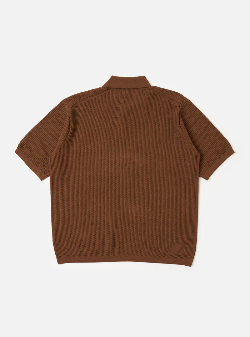 The Brown Fine Texture Tricot S/S Knit Polo is shown from the back as a flat lay against a plain white background. The image highlights the short sleeves, a neat collar, and a ribbed hem. The garment features a raised, textured rib pattern throughout the brown cotton knit.