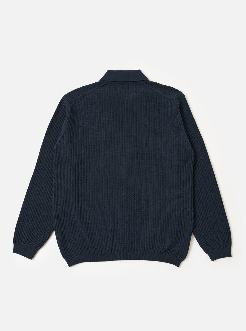 A model wears the Navy Eco Cotton Knit Jacket against a plain, light-colored background. The jacket features a textured knit construction, a five-button front closure, and two large patch pockets at the waist. The model is shown from the front, highlighting the garment's relaxed fit and ribbed detailing at the collar and cuffs.