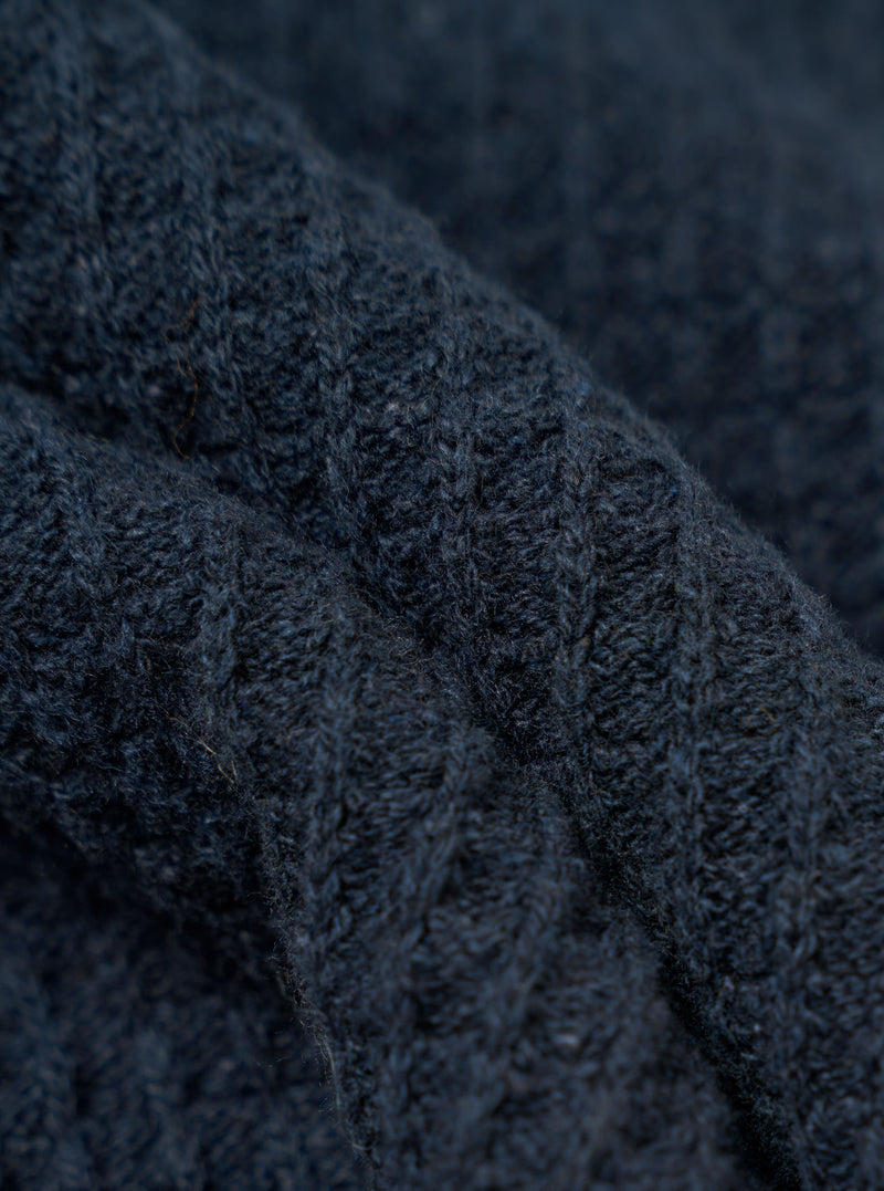 A close-up fabric swatch of the Navy Eco Cotton Knit Jacket shows the detailed texture of the dark blue knit material. The image focuses on the intricate weave and pattern of the recycled cotton threads. No model or mannequin is present.